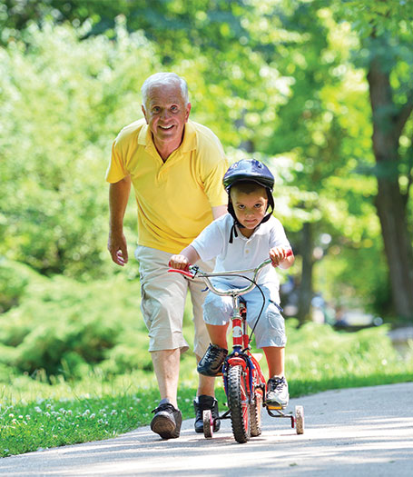 grandpa helping his grandson ride a bicycle at the park annuities for retirement options