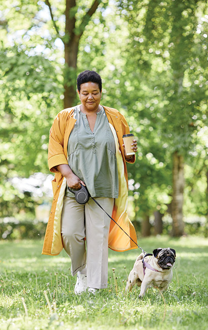 woman walking her dog in the park with a cup of coffee in her hand annuities for retirement